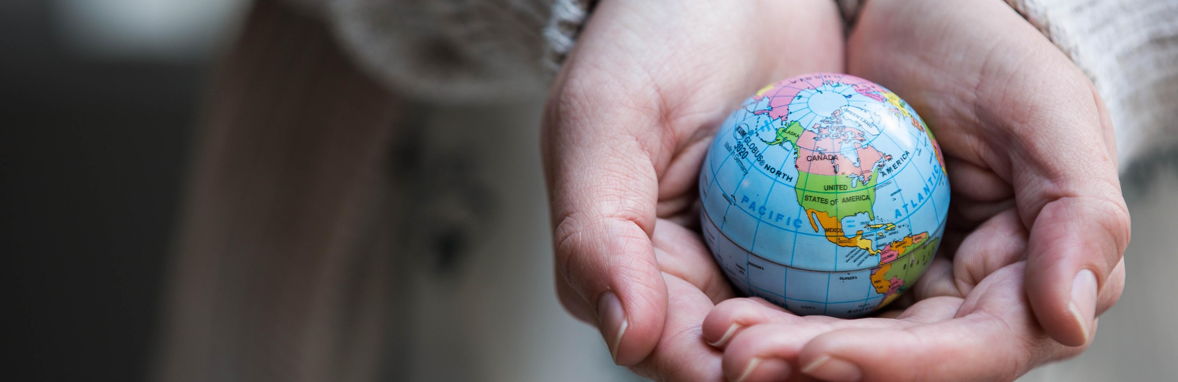 photo of hands holding small globe
