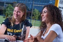 photo of students sitting at table in courtyard