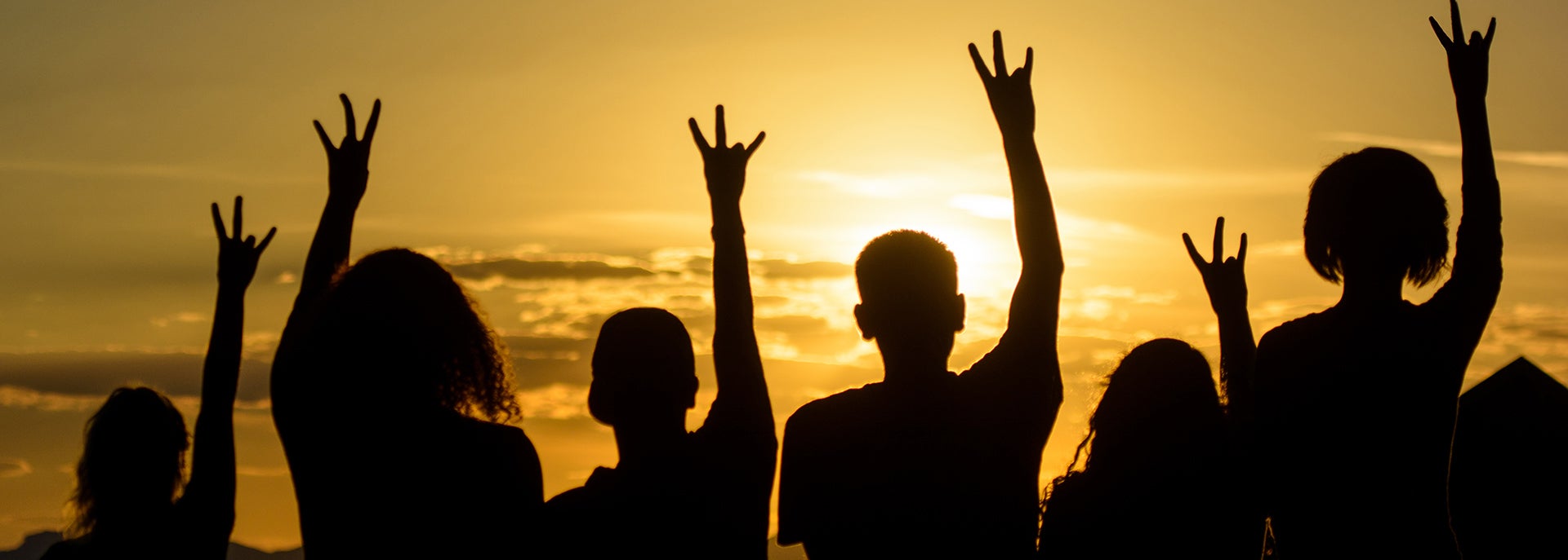photo of students making pitchfork hands against the sunset