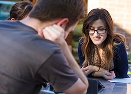 photo of students sitting at table in courtyard