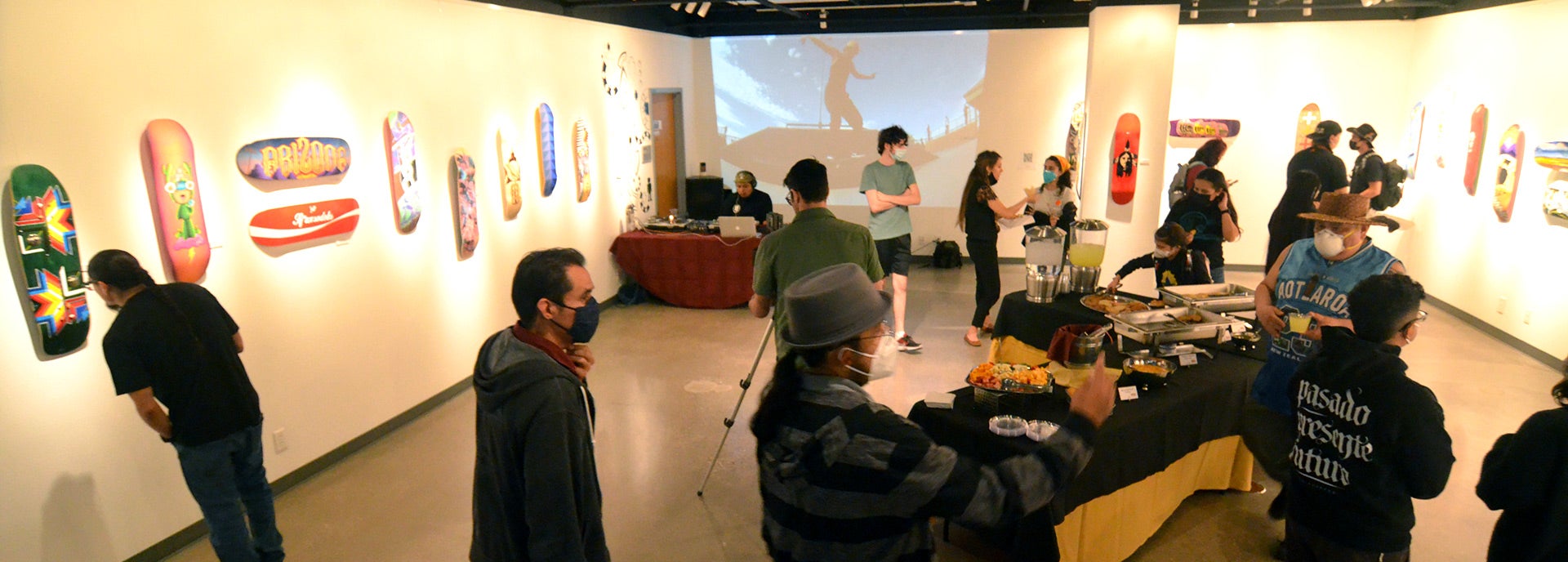 art gallery with many people wandering around looking at arts