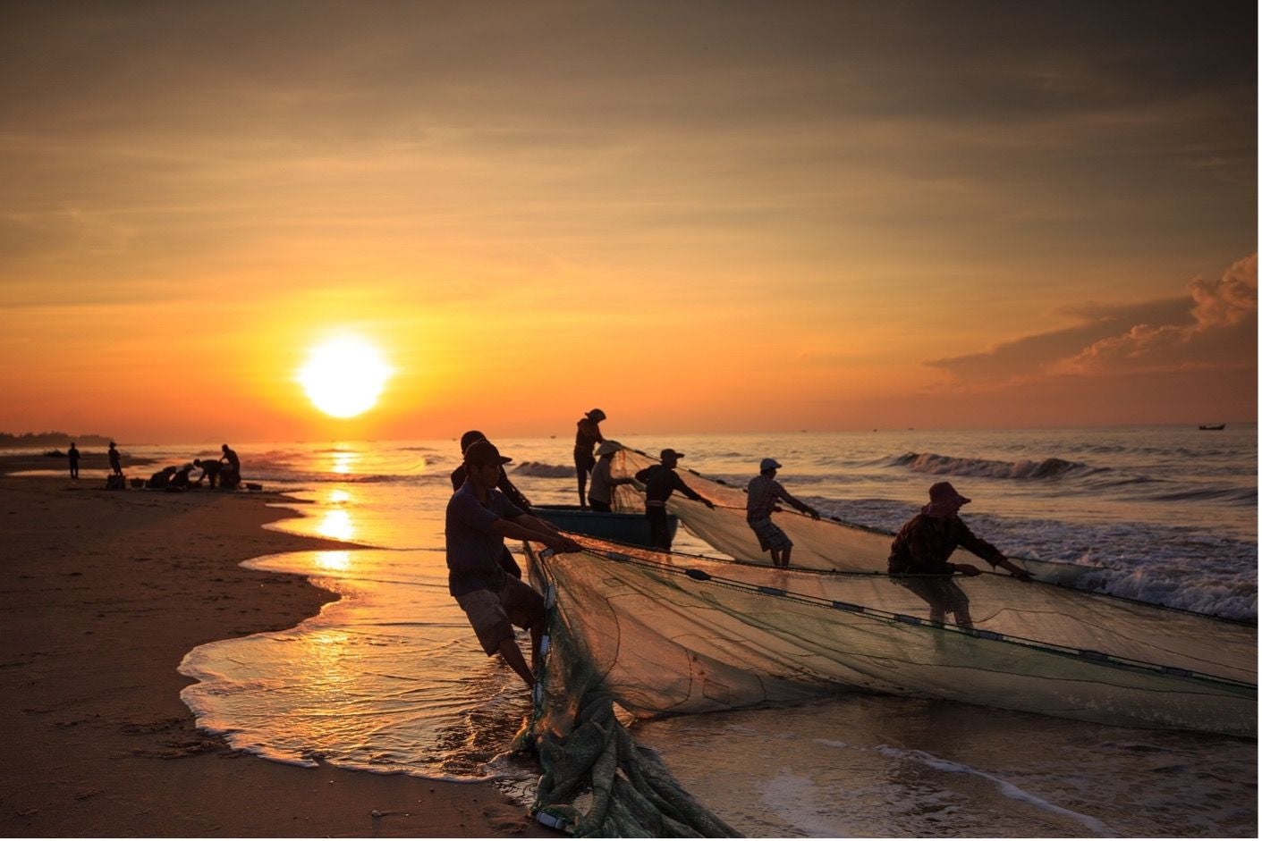 fishermen pulling in net from the beach