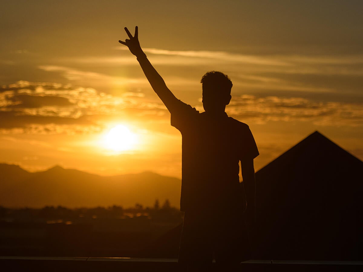 photo of student with pitchfork at sunset on the west campus