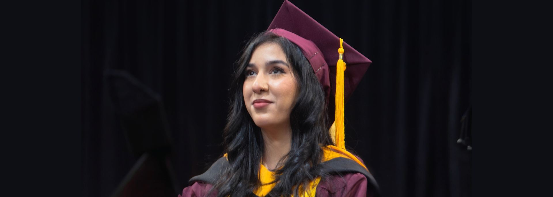 Hiba Alany in ASU regalia against a black backdrop