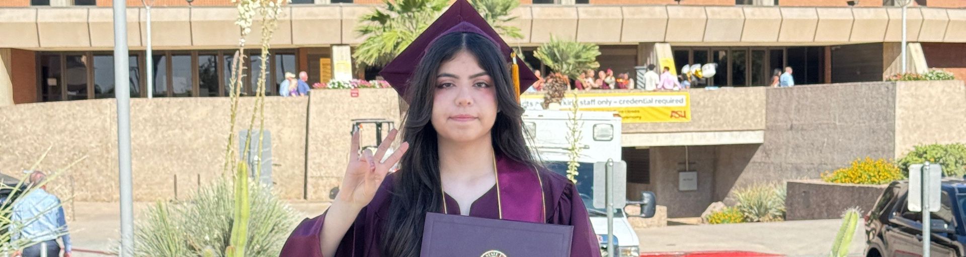 Marlene Carrasco Lechuga making a pitchfork symbol with her hand while wearing regalia 