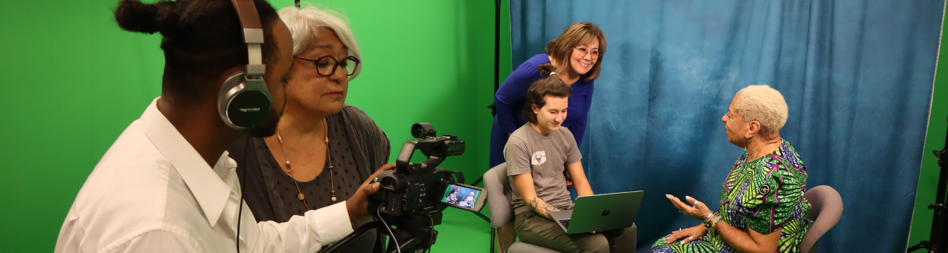 Two people filming a group of three speaking together in a studio