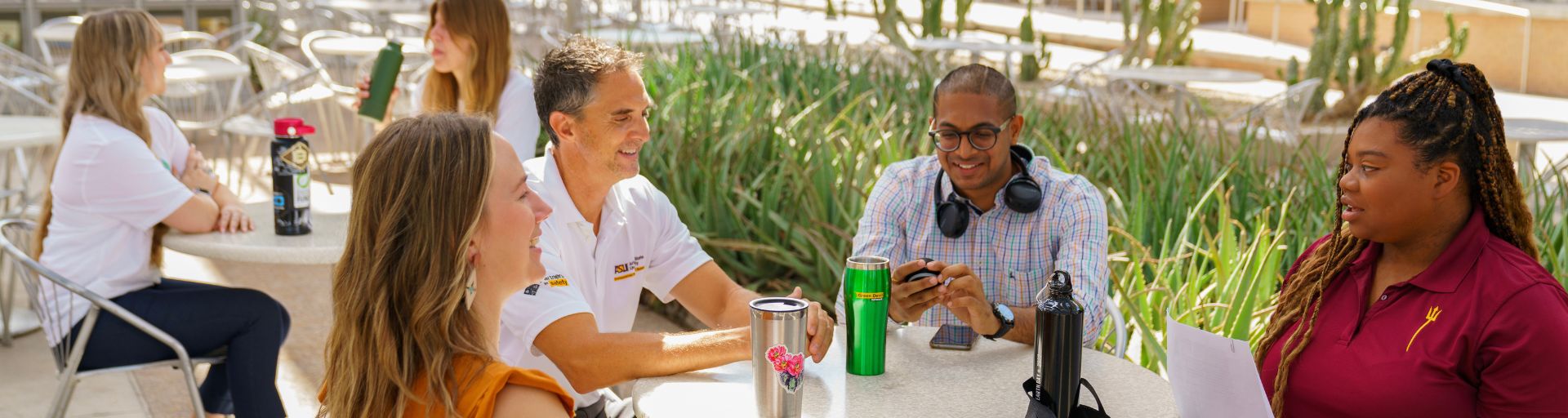 A group of people talking around a table outdoors on an ASU campus