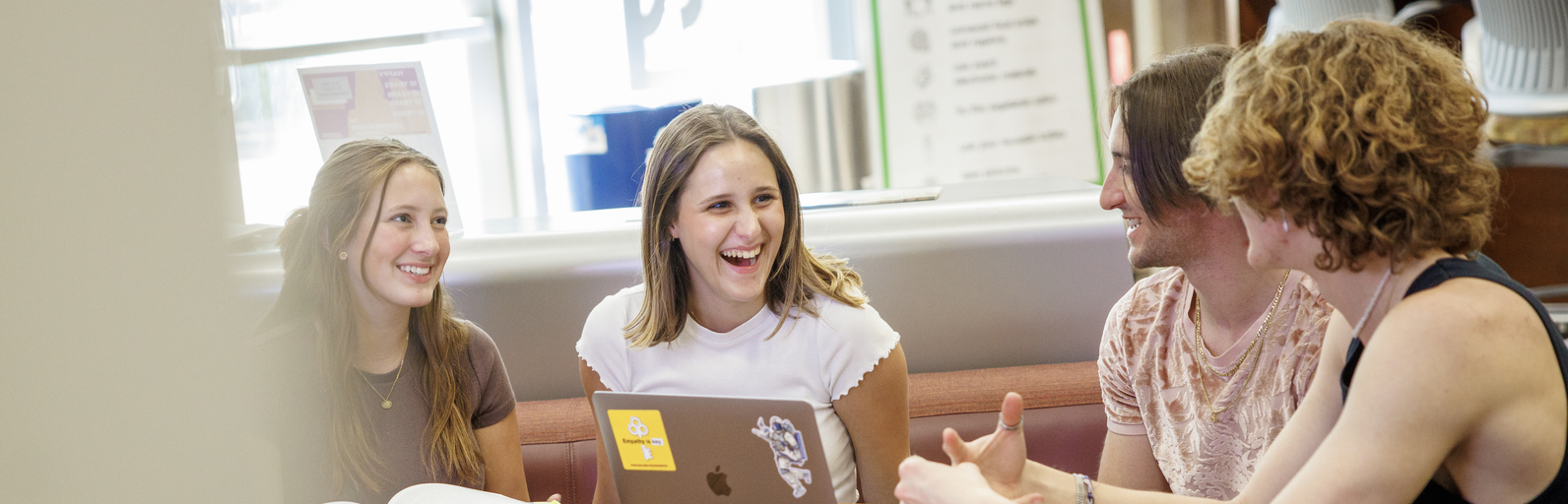 Four young adults sitting at a table, smiling and chatting.
