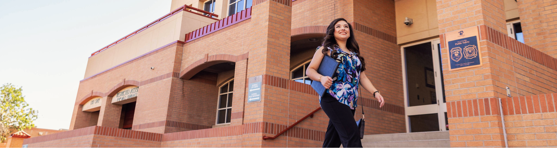 A woman walking in front of a brick public safety building.